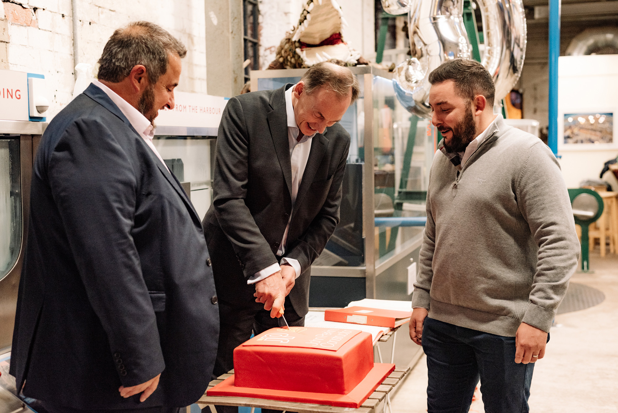 Rob Yeandle cuts the cake, flanked by Rupert Perkins and Alex Jenkins